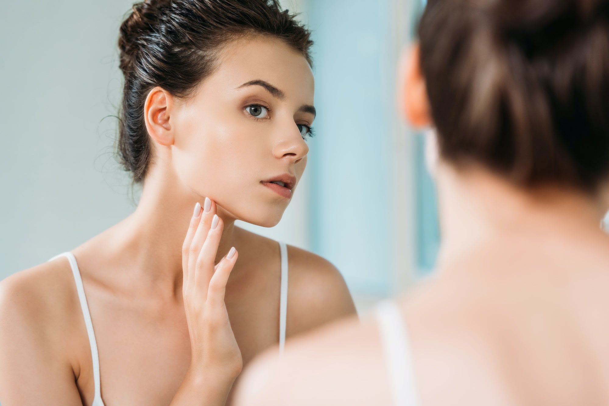 woman touching face looking at mirror