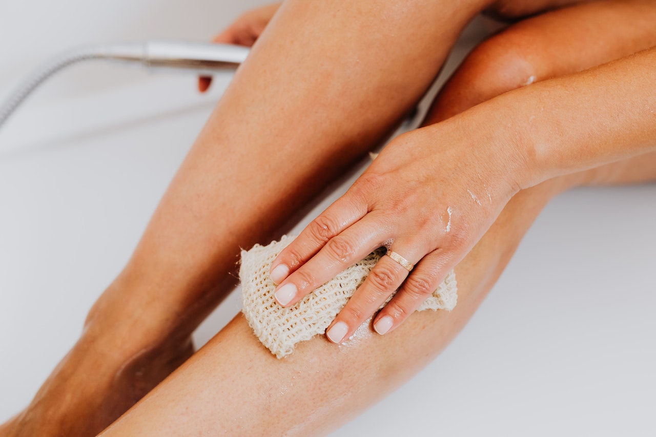 a woman is exfoliating her legs with a cloth